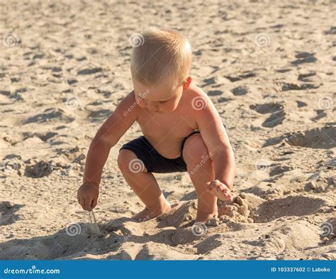 Il Ragazzo Biondo Sulla Spiaggia Gioca Con La Sabbia Fotografia Stock Immagine Di Allegro