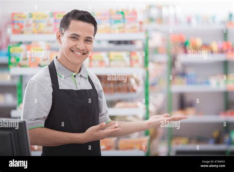 Portrait Of A Smiling Shopkeeper In A Grocery Store Welcoming Customer