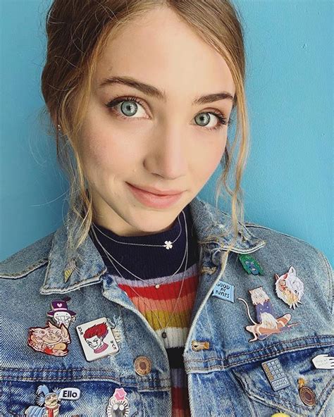 A Young Woman With Blue Eyes Wearing A Denim Jacket And Colorful Sweater Is Posing For The Camera