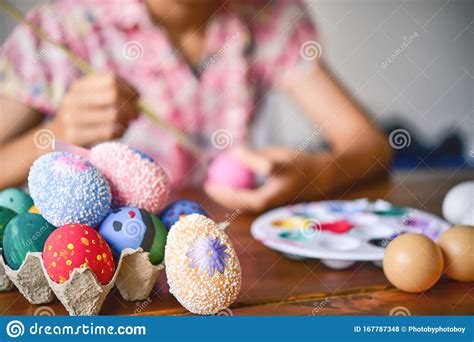 Young Girl Painting Easter Eggs For Eastertime At Home Stock Photo