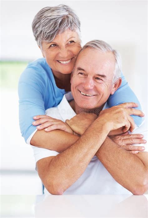 Mature Couple Embracing At Home Happy Mature Couple Embracing While Relaxing At Home Stock