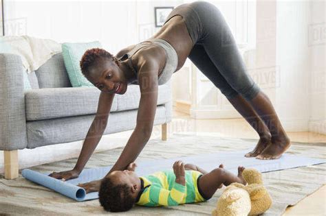 Black Mother Practicing Yoga With Baby Babe In Living Room Stock Photo Dissolve