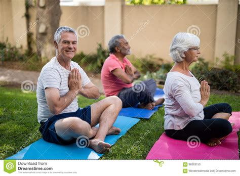 Smiling Senior Man Meditating In Prayer Position With Friends Stock