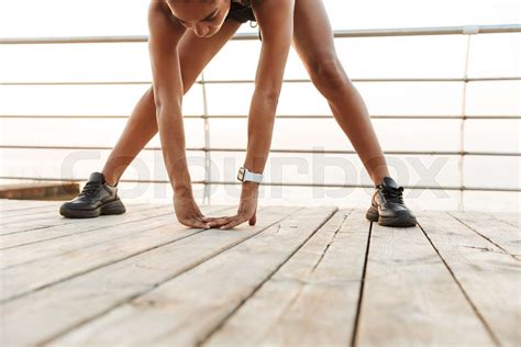 Cropped Image Of Serious Woman Bending And Stretching Her Body While Doing Workout By Seaside In