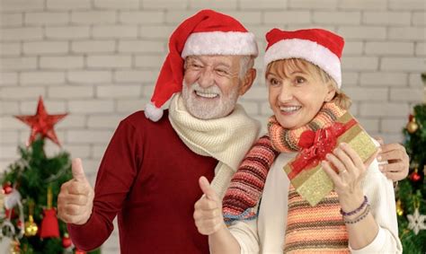 Premium Photo Gleeful Aged Man And Mature Woman In Santa Hats Looking