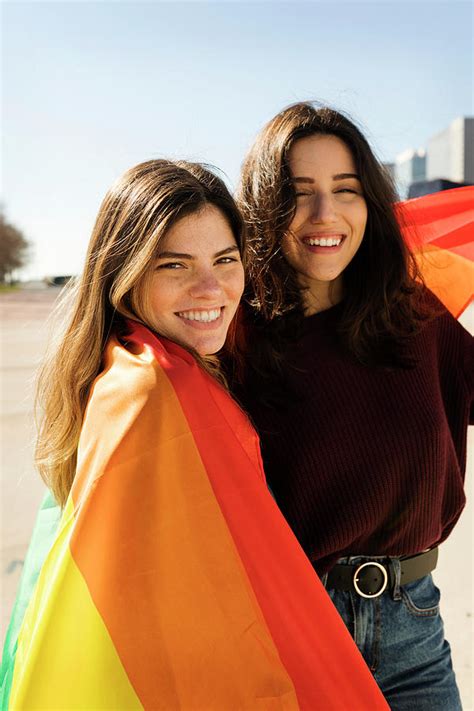 couple lesbian woman with gay pride flag smiling portrait photograph by cavan images pixels