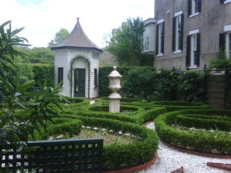 A Garden With Hedges And A Gazebo In The Middle