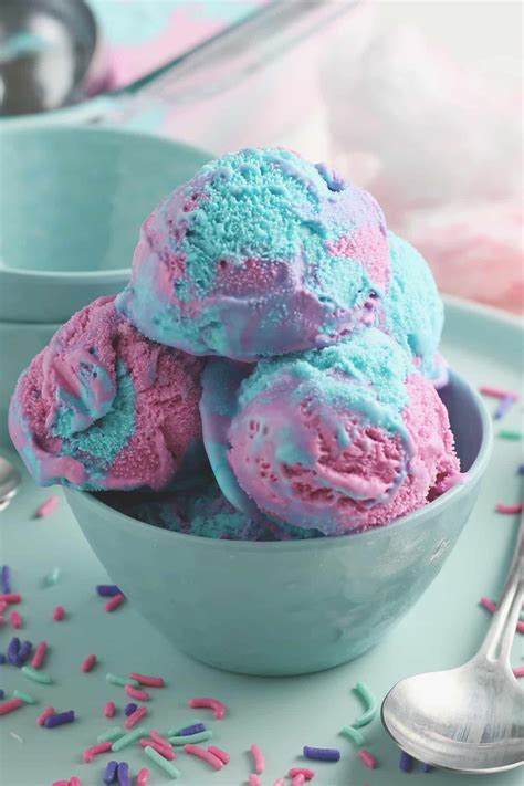 pink and blue cotton candy ice cream in a blue bowl with sprinkles surrounding it ice cream