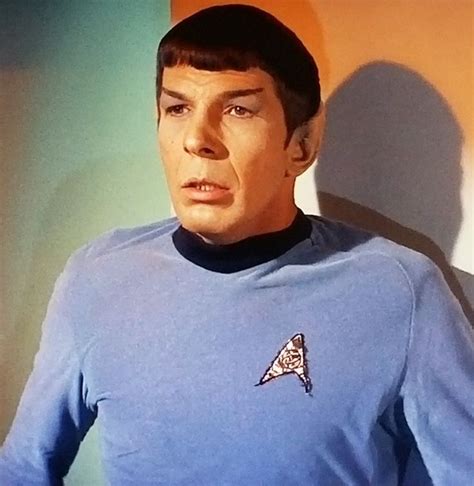 A Man In A Blue Star Trek Shirt Is Looking Off To The Side With His Hand On His Hip