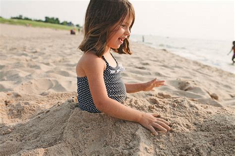 Smiling Young Girl Buried In Sand At The Beach By Stocksy Contributor