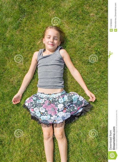 Девушка ребенка кладя в траву под солнцем лета Стоковое Изображение изображение насчитывающей