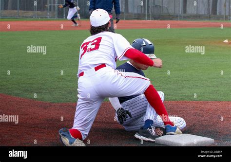 high school baseball player sliding into third base with the third baseman applying the tag and