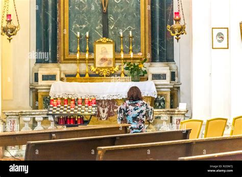 Kneeling Woman Praying In Front Of The Altar Of A Catholic Church Stock