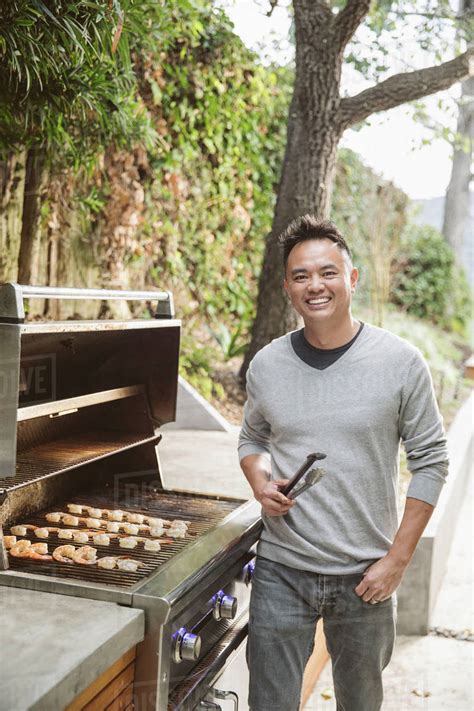 Portrait Of Smiling Chinese Man Cooking On Grille Stock Photo Dissolve