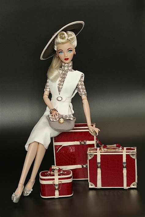 a barbie doll sitting on top of three suitcases and holding a handbag in her right hand
