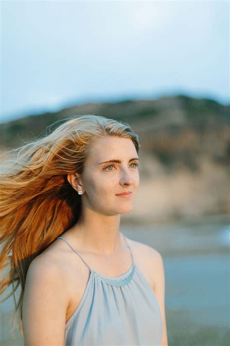 Beautiful Young Blonde Woman In Blue Dress With Hair Blowing In Wind