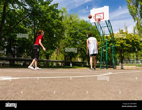 Young Athletic Couple Playing Basketball Together On Outdoor Court In