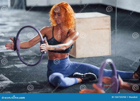 With Special Equipment Sporty Redhead Girl Have Fitness Day In Gym At Daytime Stock Photo