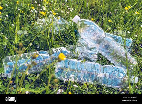 Heap Of Empty Plastic Water Bottles Amid Flowery Fieldpollution