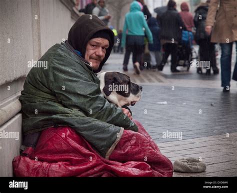 A Homeless Man Sits In The Rain With His Dog In London Stock Photo