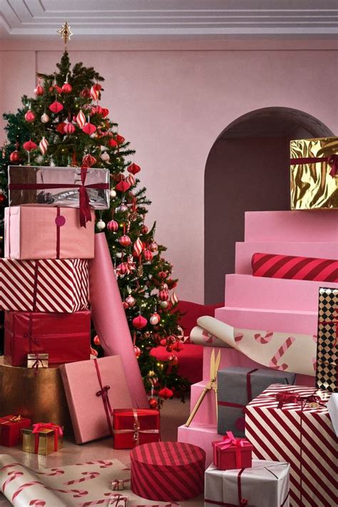 many presents are stacked next to a christmas tree in a room decorated with pink and red striped