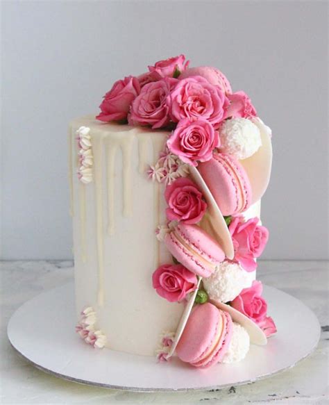 beautiful white drip cake adorned with pink flowers and macarons drip cakes beautiful cakes