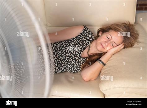 femme allongée sur le canapé avec un ventilateur devant lui donnant de l air frais en été photo