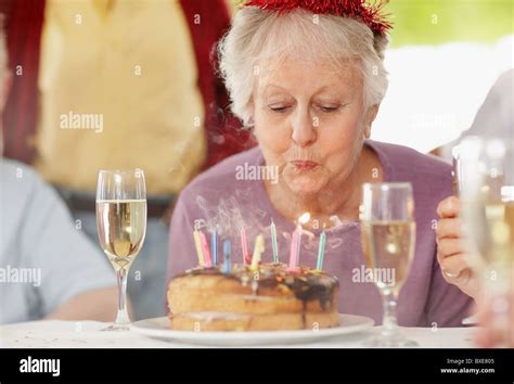 Senior Woman Blowing Out The Candles On A Birthday Cake Stock Photo Alamy