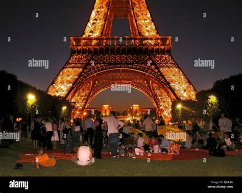 Eiffel Tower Illuminated At Night With A Party On The Champ De Mars In