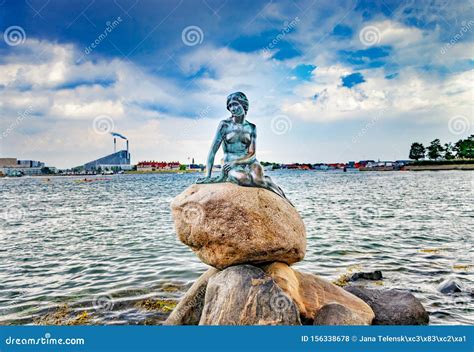 Statue Of Little Mermaid Sitting On Stone Behind It Is The Sea And The