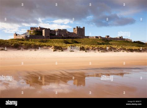 Bamburgh Castle Reflected In Wet Sand On Empty Beach Foreshore In
