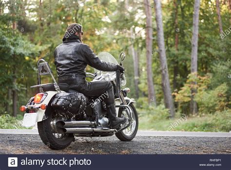 Back View Of Bearded Biker In Black Leather Clothing Riding On Cruiser