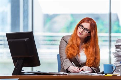 The Redhead Businesswoman Sitting At Her Desk In The Office Stock Image