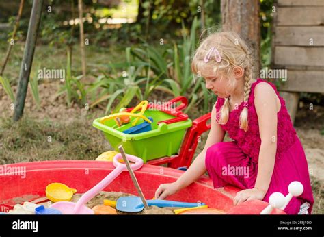 Little Adorable Child Playing In Sandpit On The Playground Stock Photo