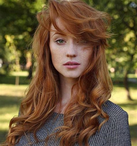 A Woman With Long Red Hair And Freckled Bangs Is Posing For The Camera