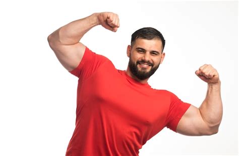 Free Photo Sportive Man In Red Shirt Demonstrating His Arm Muscles