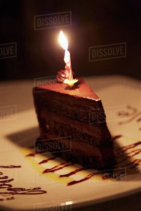 A Slice Of Chocolate Cake With A Birthday Candle Stock Photo Dissolve