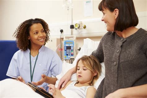 Nurse Talking To Mother And Daughter In Hospital Bed Stock Photo