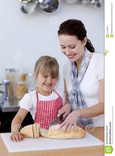 Mother Teaching Daughter How To Cut Bread Stock Image