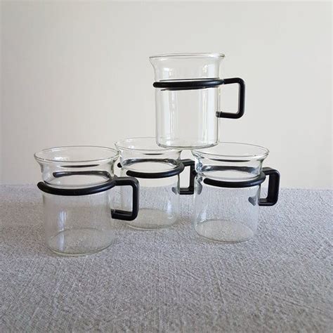 Four Glass Cups With Black Handles Are Stacked On Top Of Each Other