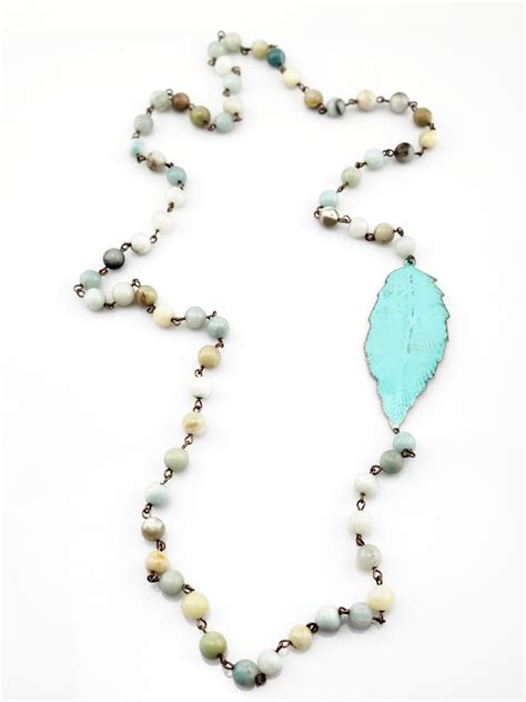 A Long Necklace With Beads And A Turquoise Leaf Pendant On It S End Is