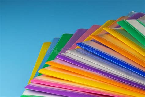 A Row Of Multi Colored Plastic Folders For Paper On A Blue Background