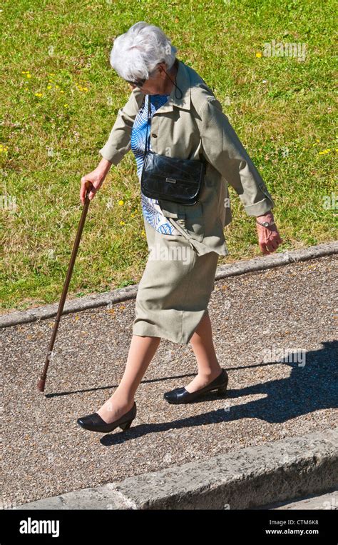 Old Woman With Walking Stick Stepping Off Pavement France Stock Photo