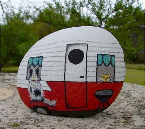 A Painted Rock With A Camper And Two Cats Sitting On Its Side