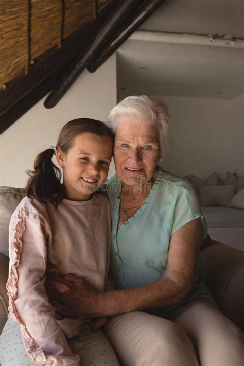 Grandmother And Granddaughter Embracing Each Other In Living Room Stock