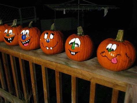 Five Pumpkins With Faces Painted On Them Are Lined Up In A Row Outside