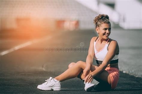Attractive Sporty Woman Sitting Confident On Stadium Tracks On A Sunny