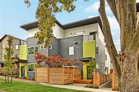 a row of multi - family houses with trees and grass in the foreground
