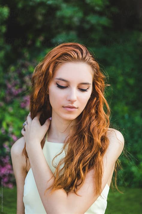 Beautiful Young Redhead Arranging Her Long Hair In A Natural Env By Stocksy Contributor