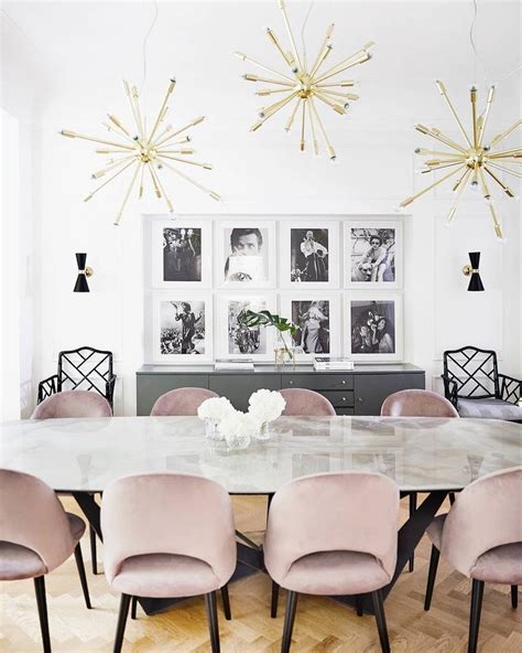 A Dining Room Table With Pink Chairs And Pictures On The Wall